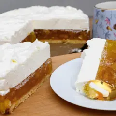Pyszny tort z warstwą owocową i puszystym kremem śmietankowym do tortu. Na talerzyku kawałek z widelcem.