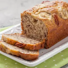 Pyszny chlebek bananowy fit z orzechami pekan i plasterkami banana na wierzchu, pokrojony na kromki.