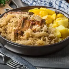 Pyszne żeberka w kapuście z ziemniakami, podane w misie. Danie wygląda apetycznie i sycąco.