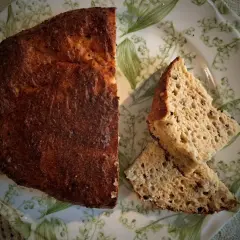 Pyszny chleb keto przepis na talerzu z konwaliami. Złocista skórka i puszysty środek.