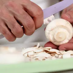 Ręce obierają pieczarkę, usuwając skórkę. Czy pieczarki trzeba obierać? Zależy od preferencji, ale często się je obiera.