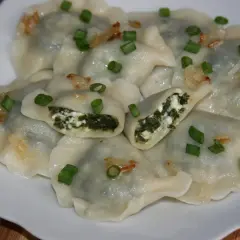 Pyszne pierogi ze szpinakiem i serem, posypane szczypiorkiem i skwarkami. Idealne na obiad!