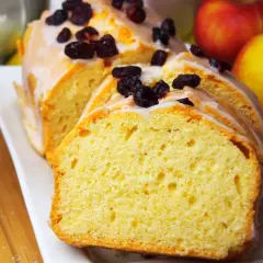 Szybka babka wilgotna, polana lukrem i posypana żurawiną, obok jabłek. Idealna na deser.