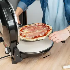 Osoba wkłada pizzę do pieca. Zastanawiasz się, w jakiej temperaturze piec pizzę? Ten piec jest idealny do domowych wypieków.