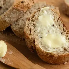 Kromka chleba z masłem, idealna do odświeżenia smaku. Masło na drewnianej desce.