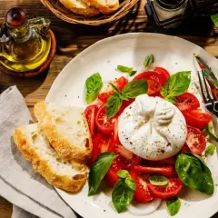 Pyszna burrata co to? Świeża, kremowa burrata z pomidorami, bazylią i chrupiącym pieczywem. Idealna na lekki posiłek.