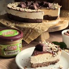 Pyszne ciasto Kinder Bueno z kremem i orzechami, obok słoiczek pasty z orzechów laskowych.