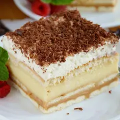 Pyszne ciasto 3 bit z kremem budyniowym, biszkoptem i bitą śmietaną, posypane czekoladą.