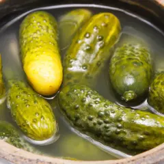 Ogórki kiszone w glinianym naczyniu. Kluczowe jest ile soli na litr wody do ogórków kiszonych, by były idealne.