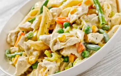 Penne z kurczakiem w kremowym sosie, z groszkiem, kukurydzą i fasolką szparagową. Pyszne danie obiadowe.