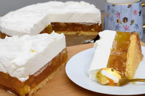 Pyszny tort z warstwą owocową i puszystym kremem śmietankowym do tortu. Na talerzyku kawałek z widelcem.
