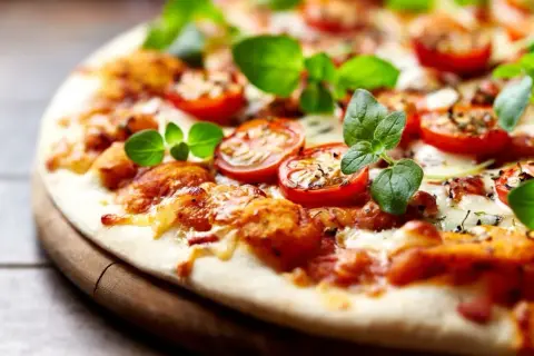 Pyszna pizza bez drożdży z pomidorkami koktajlowymi i świeżą bazylią, idealna na szybki obiad.