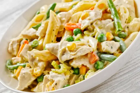 Penne z kurczakiem w kremowym sosie, z groszkiem, kukurydzą i fasolką szparagową. Pyszne danie obiadowe.