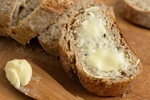Kromka chleba z masłem, idealna do odświeżenia smaku. Masło na drewnianej desce.