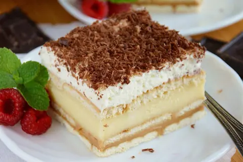 Pyszne ciasto 3 bit z kremem budyniowym, biszkoptem i bitą śmietaną, posypane czekoladą.