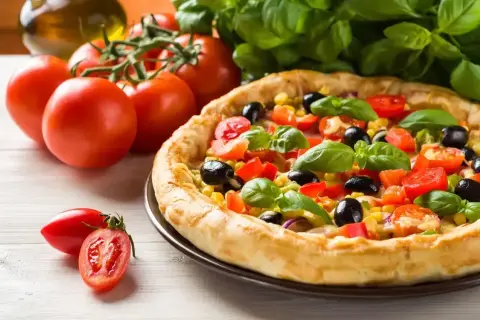 Pyszna pizza z pomidorami, oliwkami i kukurydzą, obok świeże pomidory i bazylia. Idealna na letni obiad.