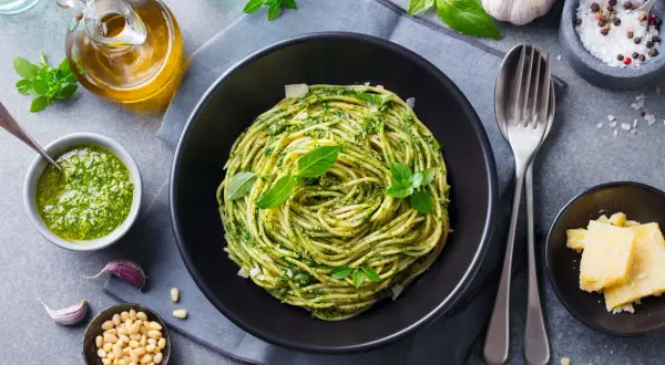 Pyszny obiad bez mięsa: spaghetti z pesto, świeżą bazylią, orzeszkami pinii i parmezanem.