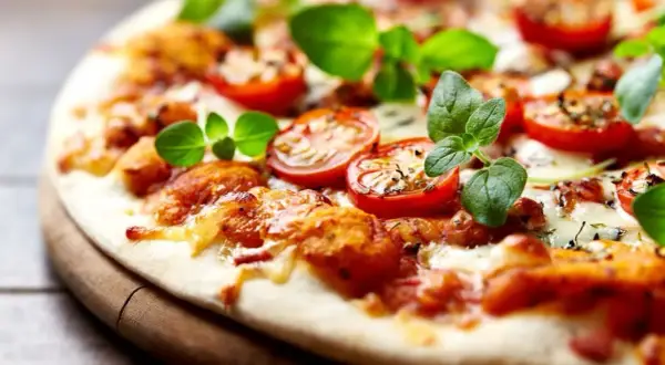 Pyszna pizza bez drożdży z pomidorkami koktajlowymi i świeżą bazylią, idealna na szybki obiad.