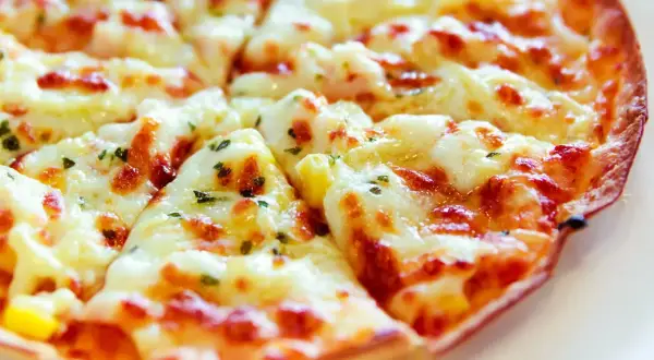 Pyszna, gorąca pizza z patelni, z ciągnącym się serem i ziołami, idealna na szybki obiad.