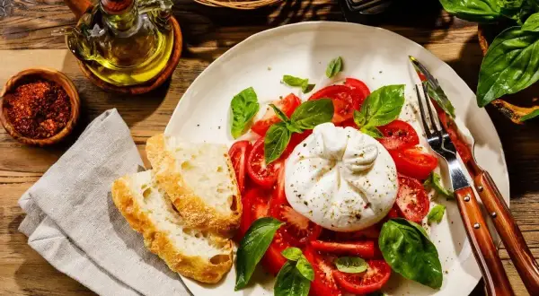 Pyszna burrata co to? Świeża, kremowa burrata z pomidorami, bazylią i chrupiącym pieczywem. Idealna na lekki posiłek.