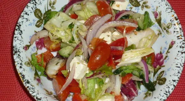 Pyszna sałatka z mix sałat, pomidorów, ogórka, sera feta i czerwonej cebuli, doprawiona ziołami.