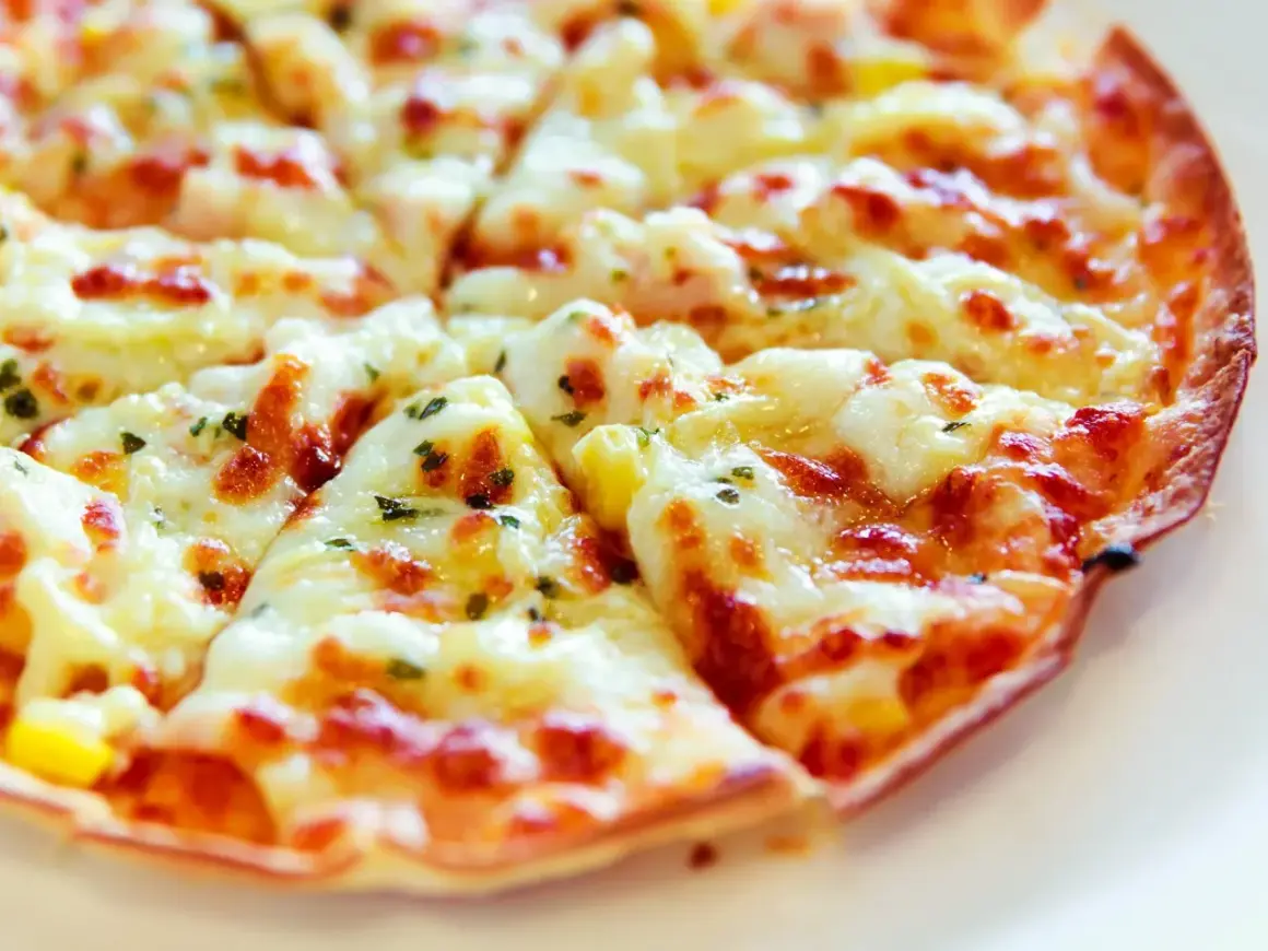 Pyszna, gorąca pizza z patelni, z ciągnącym się serem i ziołami, idealna na szybki obiad.