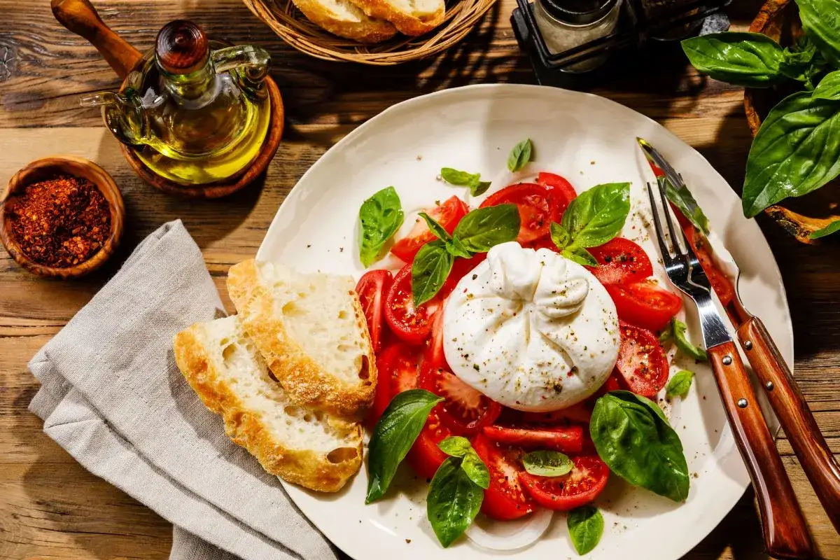 Pyszna burrata co to? Kremowy ser otoczony pomidorami i bazylią, podany z chrupiącym pieczywem. Idealna na lekki posiłek.