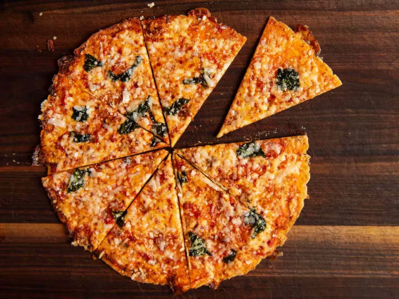 Chrupiąca pizza z tortilli, pokrojona w tr&oacute;jkąty, z ciągnącym się serem i zielonymi listkami bazylii.
