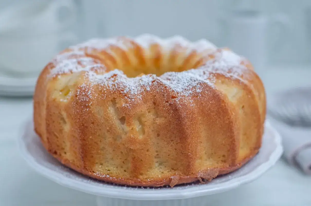 Szybka babka wilgotna, oprószona cukrem pudrem, prezentuje się apetycznie na białej paterze. Idealna na deser.