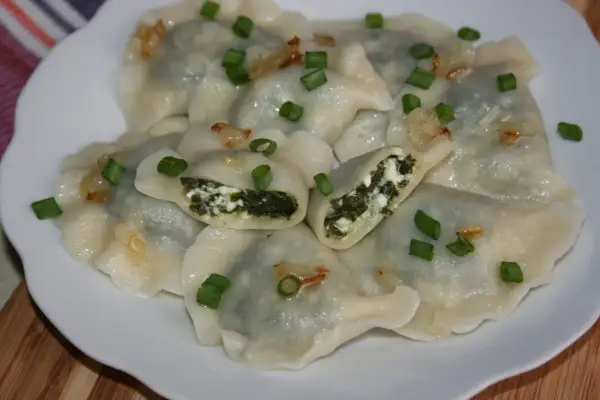 Pyszne pierogi ze szpinakiem i serem, posypane szczypiorkiem i skwarkami. Idealne na obiad!