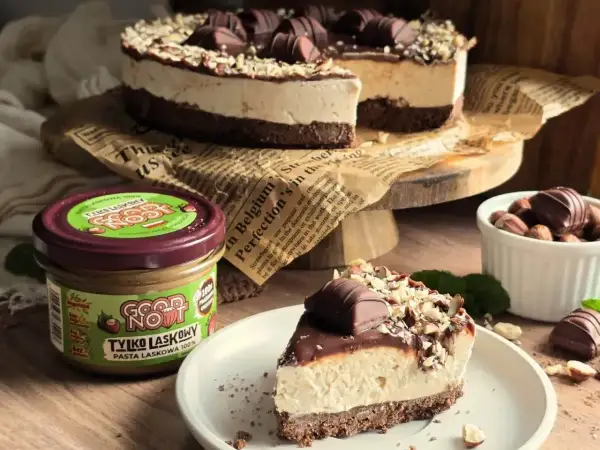 Pyszne ciasto Kinder Bueno z kremem i orzechami, obok słoiczek pasty z orzechów laskowych.